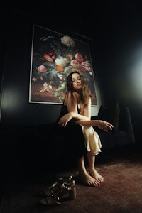a woman sitting on a couch in front of a painting